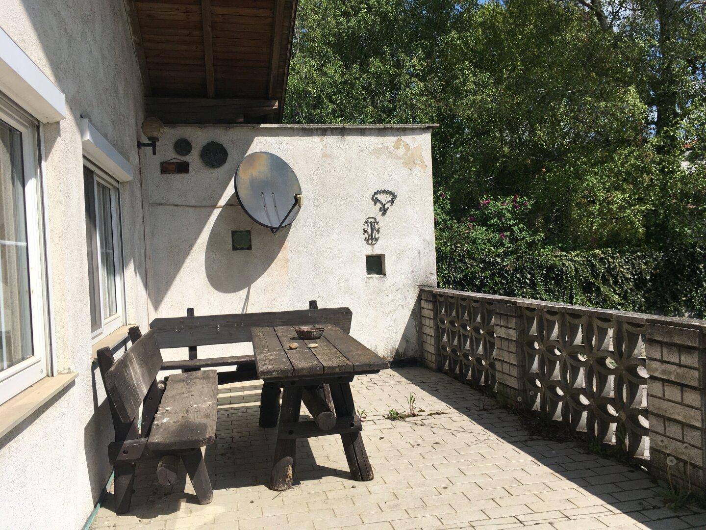 Gemütliche Terrasse mit rustikalen Holzmöbeln und Blick ins Grüne.