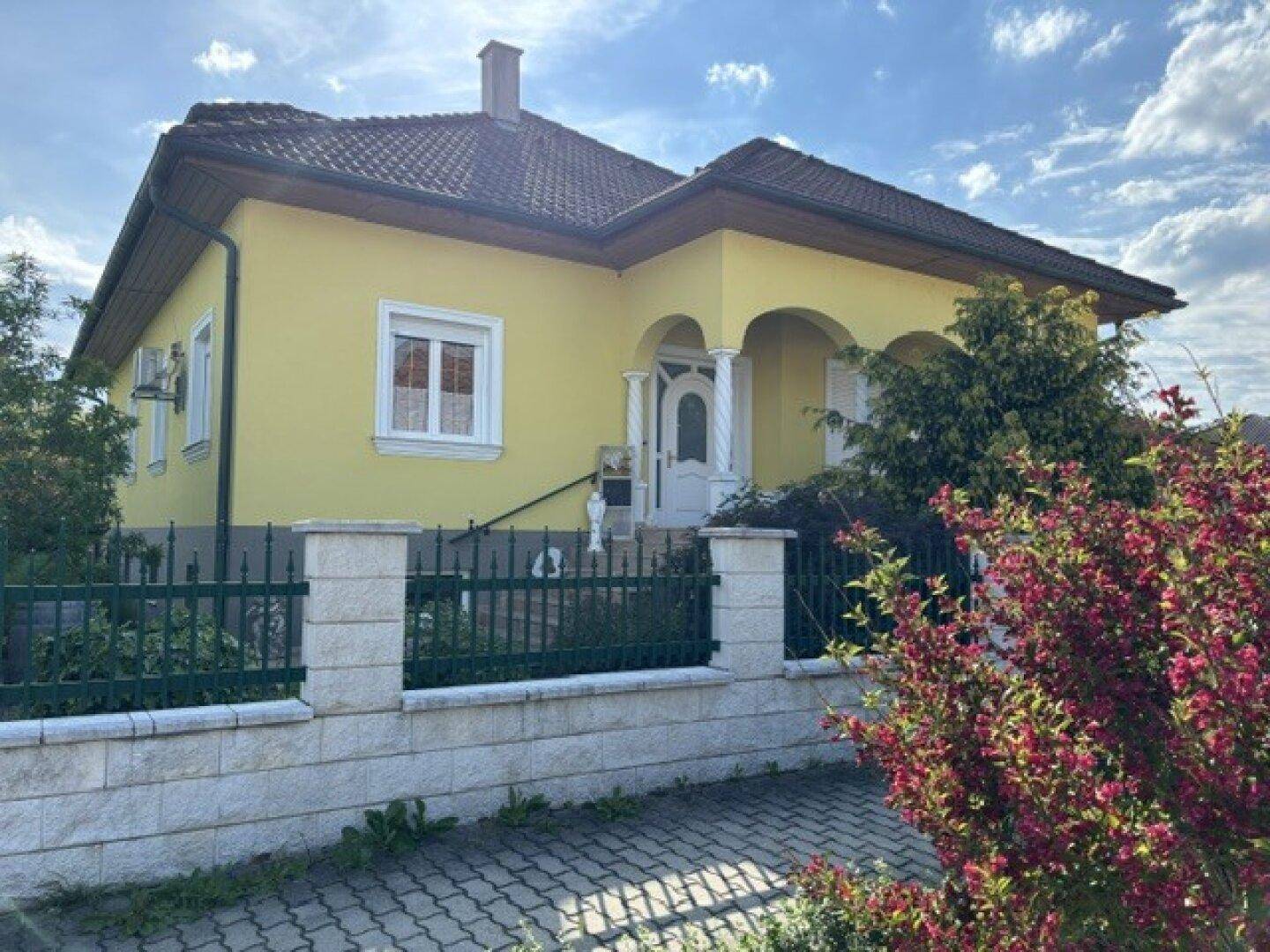 Attraktive gelbe Hausfassade mit traditionellem Dach und gepflegtem Vorgarten.