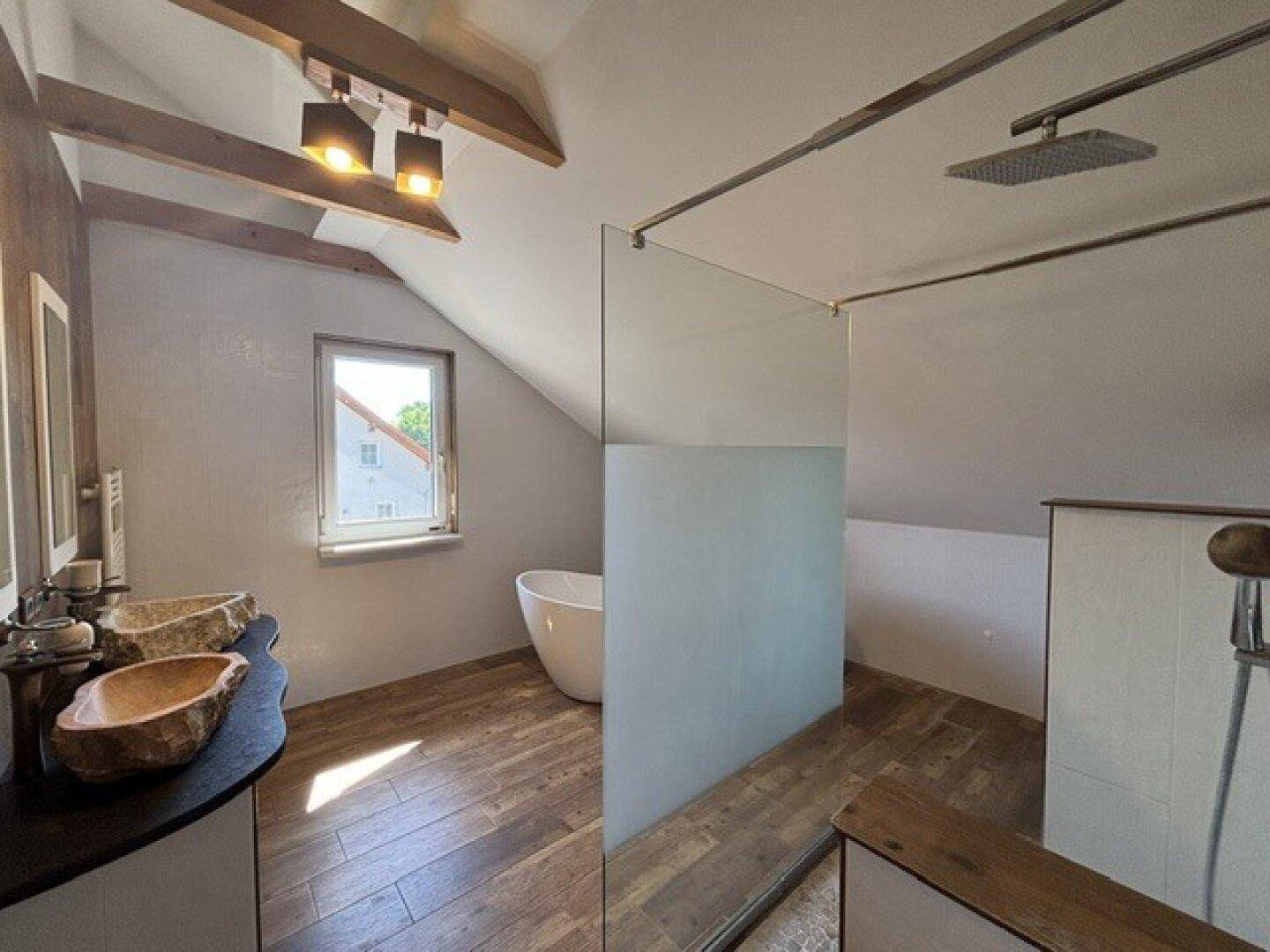 Modernes Dachgeschossbad mit freistehender Badewanne, begehbarer Dusche und zwei Waschbecken.