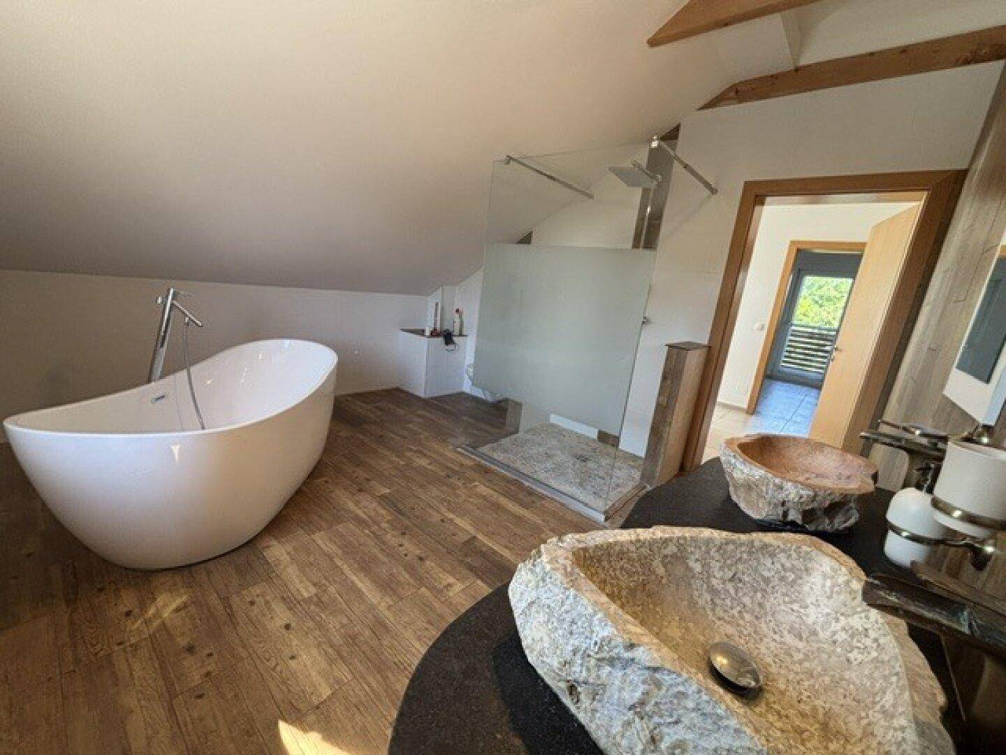 Geräumiges Dachgeschossbad mit freistehender Wanne, begehbarer Dusche und einzigartigen Steinwaschbecken.