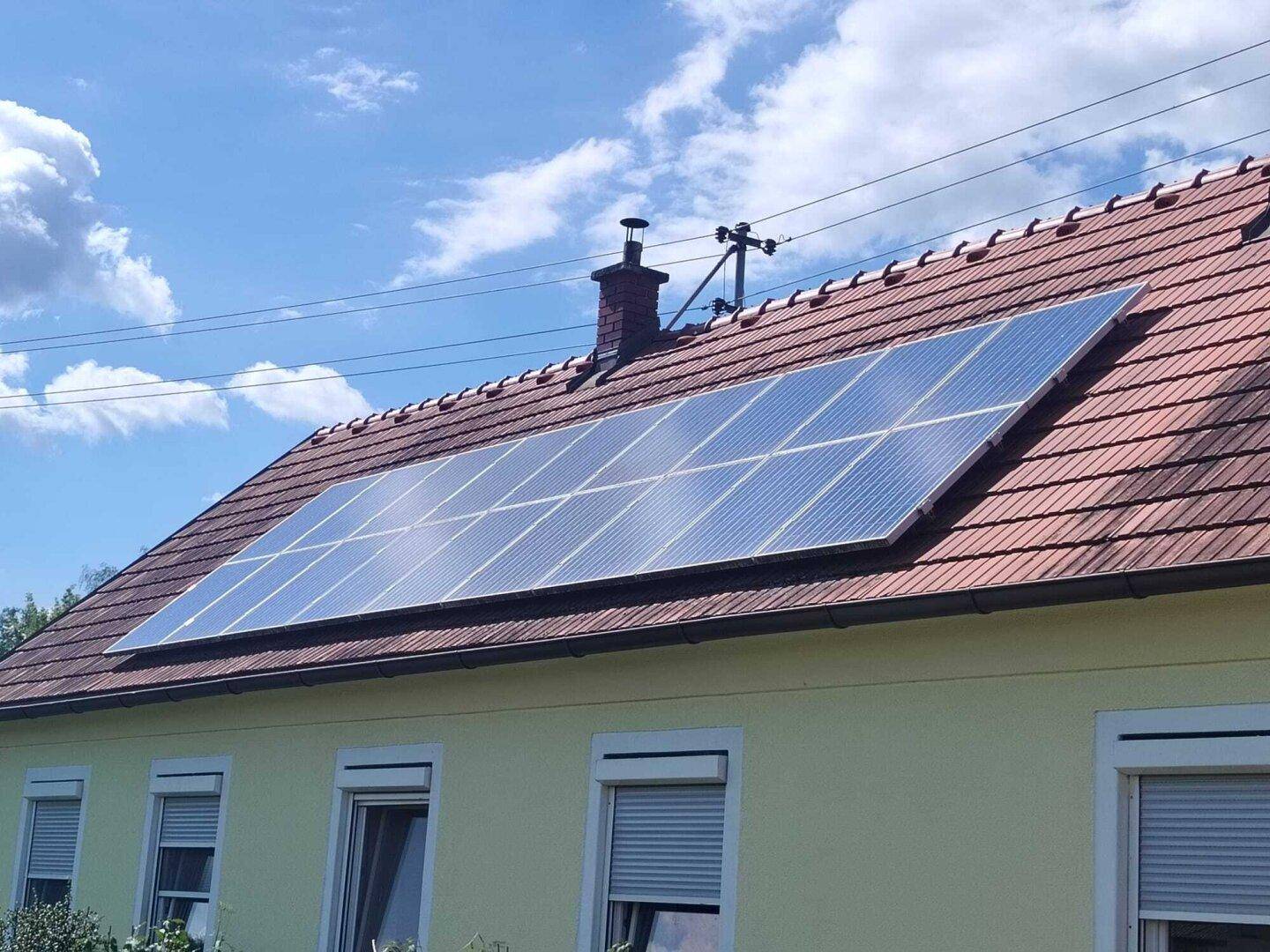 Dach des Hauses mit installierten Photovoltaik-Modulen unter klarem Himmel.