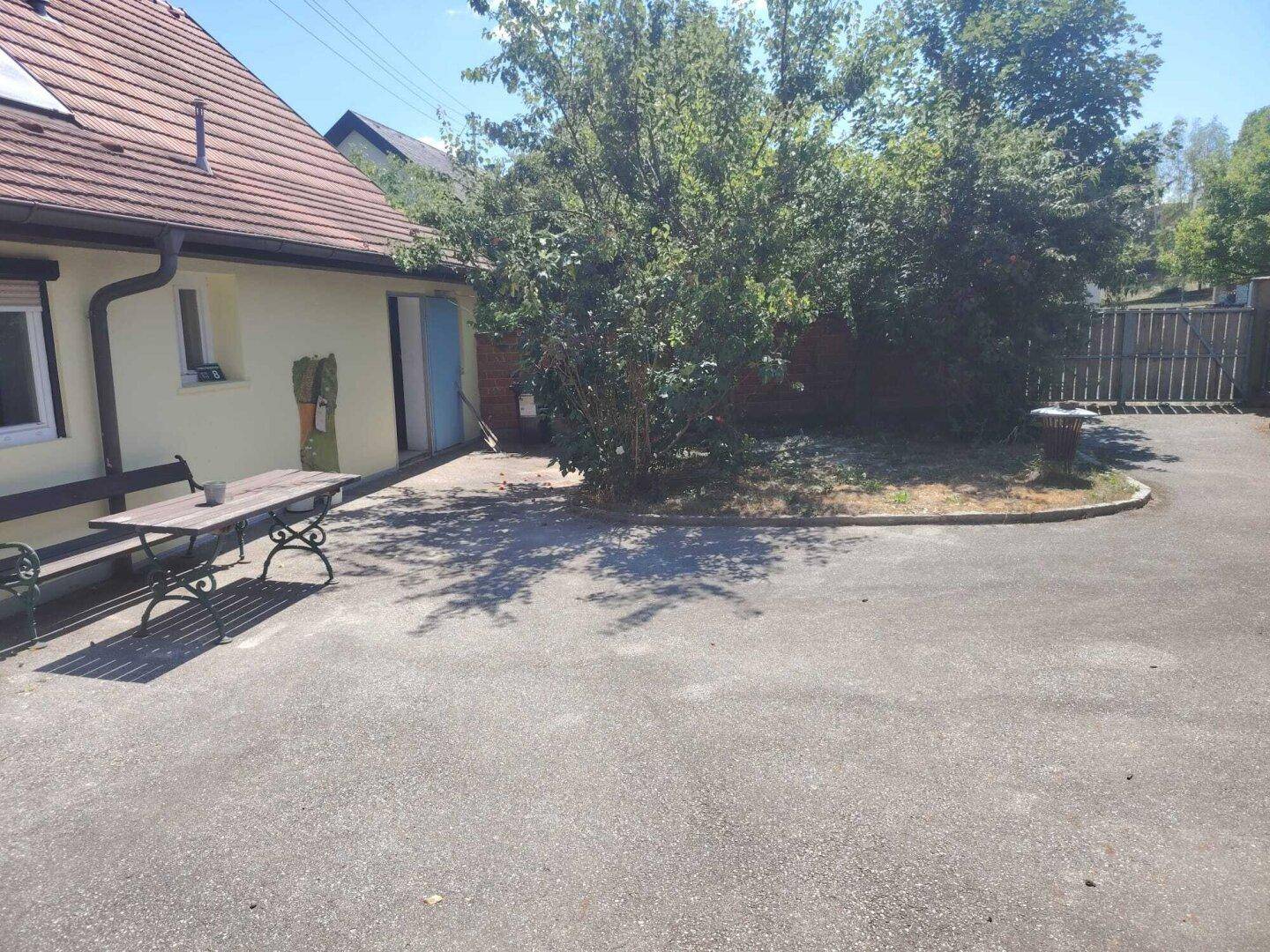 Geräumiger Hof mit Sitzbank und Bäumen, ideal für entspannte Stunden im Freien.