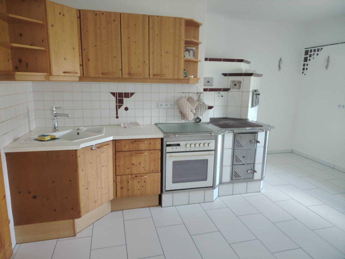 Rustikale Küche mit Holzschränken, weißem Fliesenspiegel und traditionellem Herd.