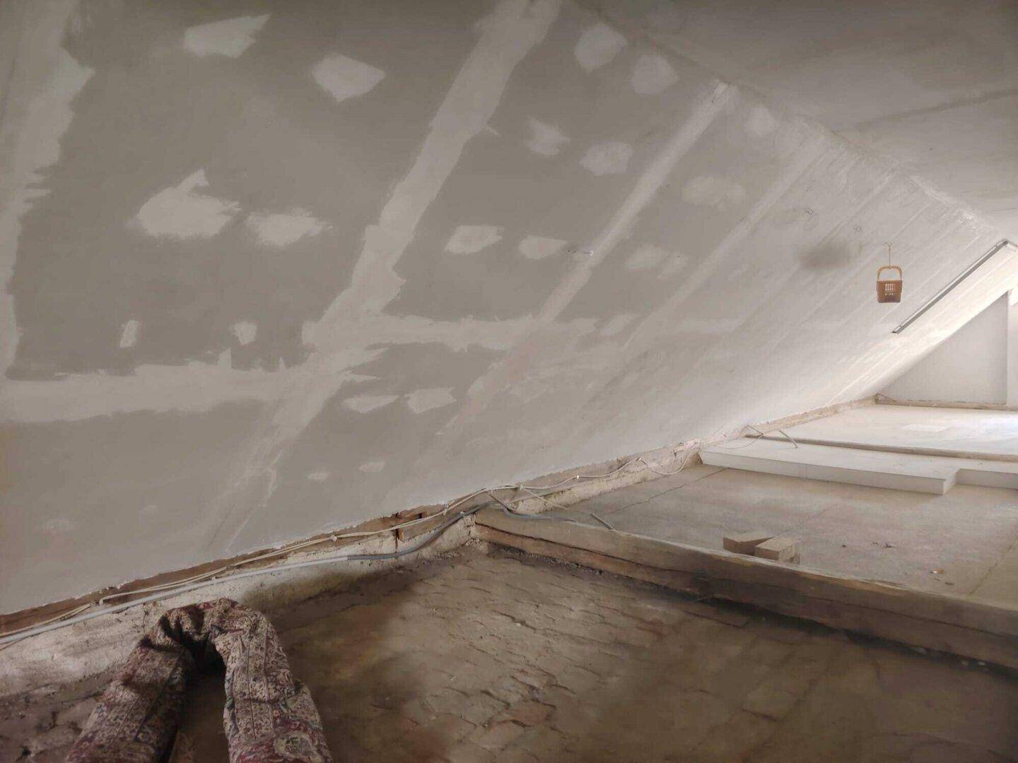 Unausgebauter Dachboden mit sichtbaren Dachschrägen und Holzbalken.
