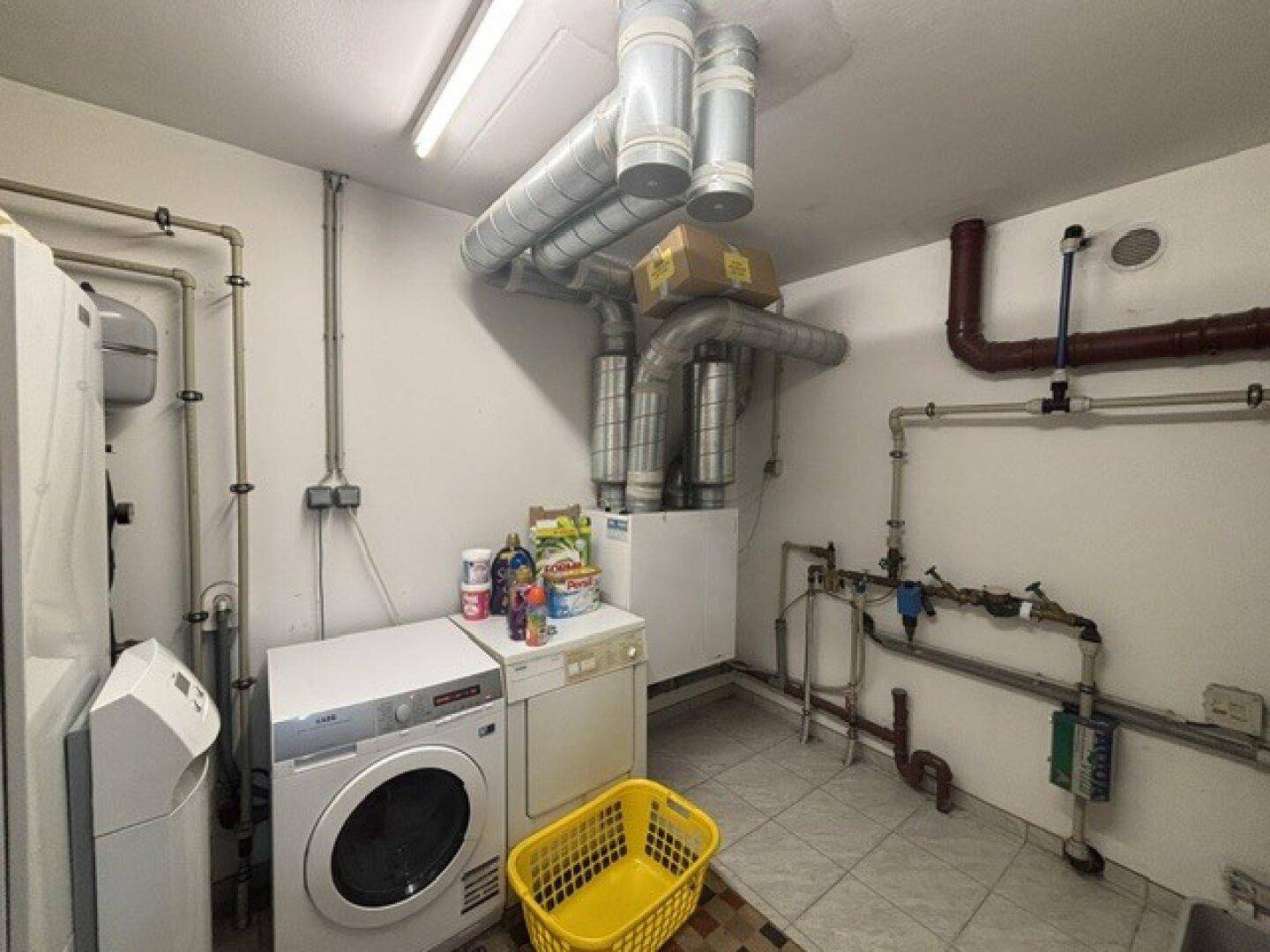 Hauswirtschaftsraum im Keller mit Waschmaschine, Trockner und Heizungsinstallationen.