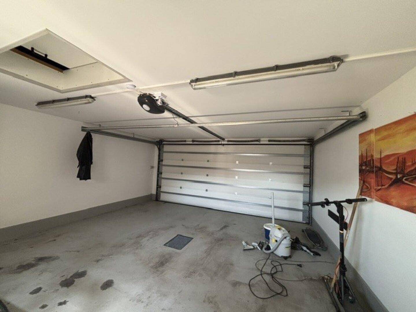 Geräumige Garage mit automatischem Tor und Betonboden.
