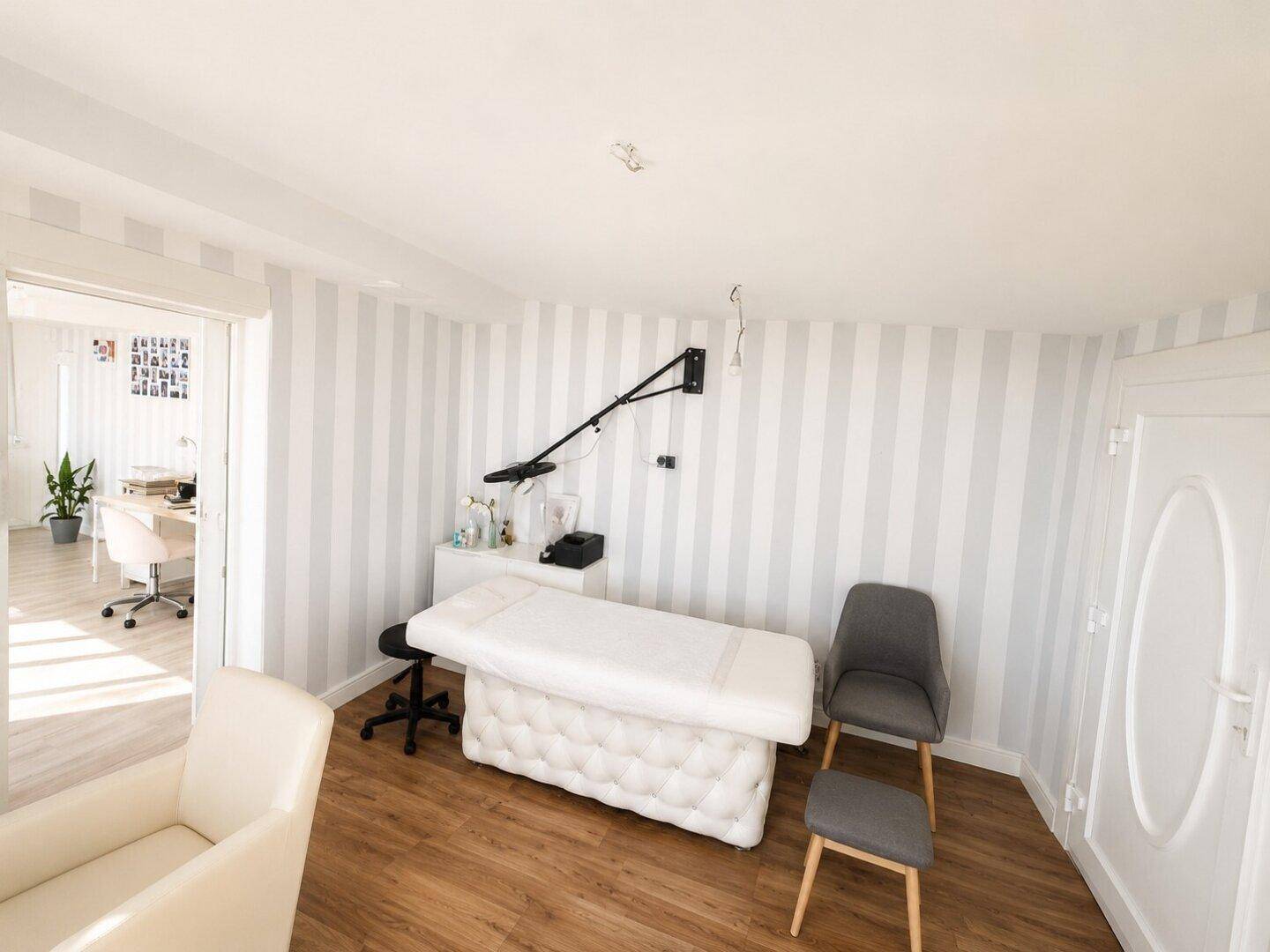Helles Arbeitszimmer mit Holzboden, gestreiften Wänden und Blick in einen weiteren Raum.