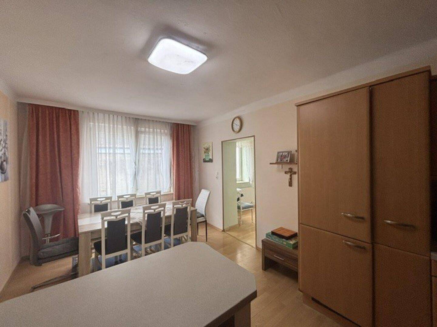 Essbereich in der Wohnküche mit großem Esstisch und einem hohen Holzschrank.