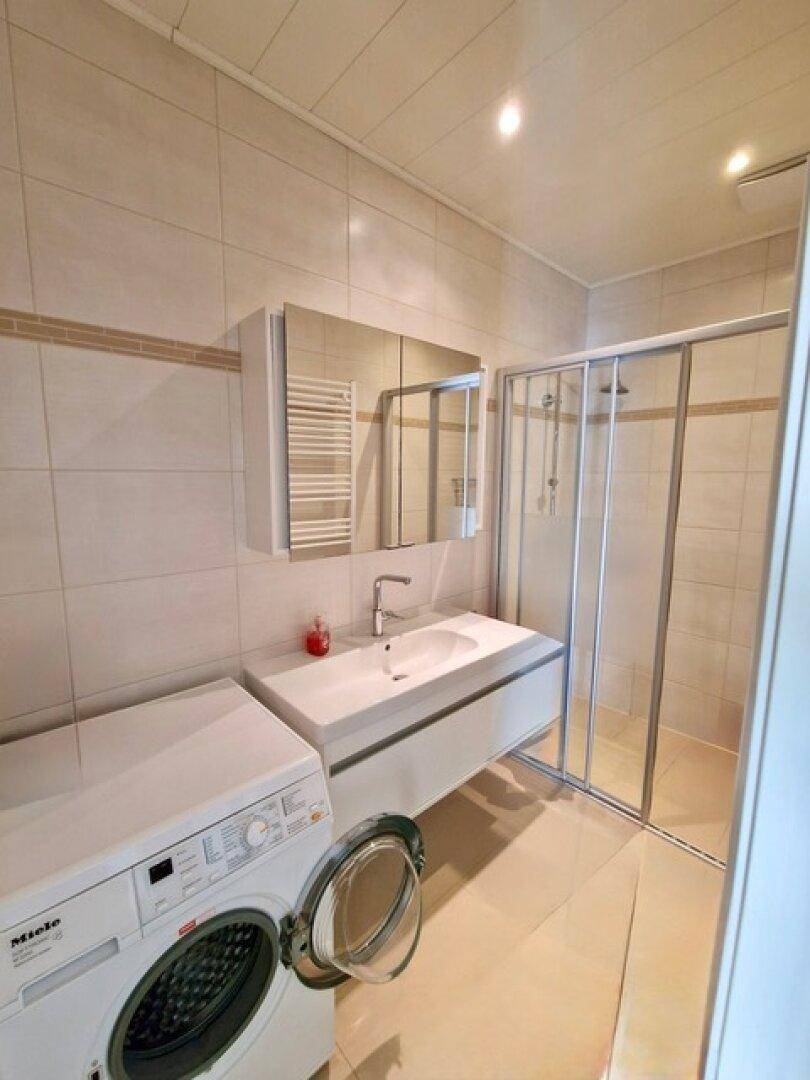 Modernes Badezimmer mit Duschkabine, Einzelwaschbecken und beheiztem Handtuchhalter.