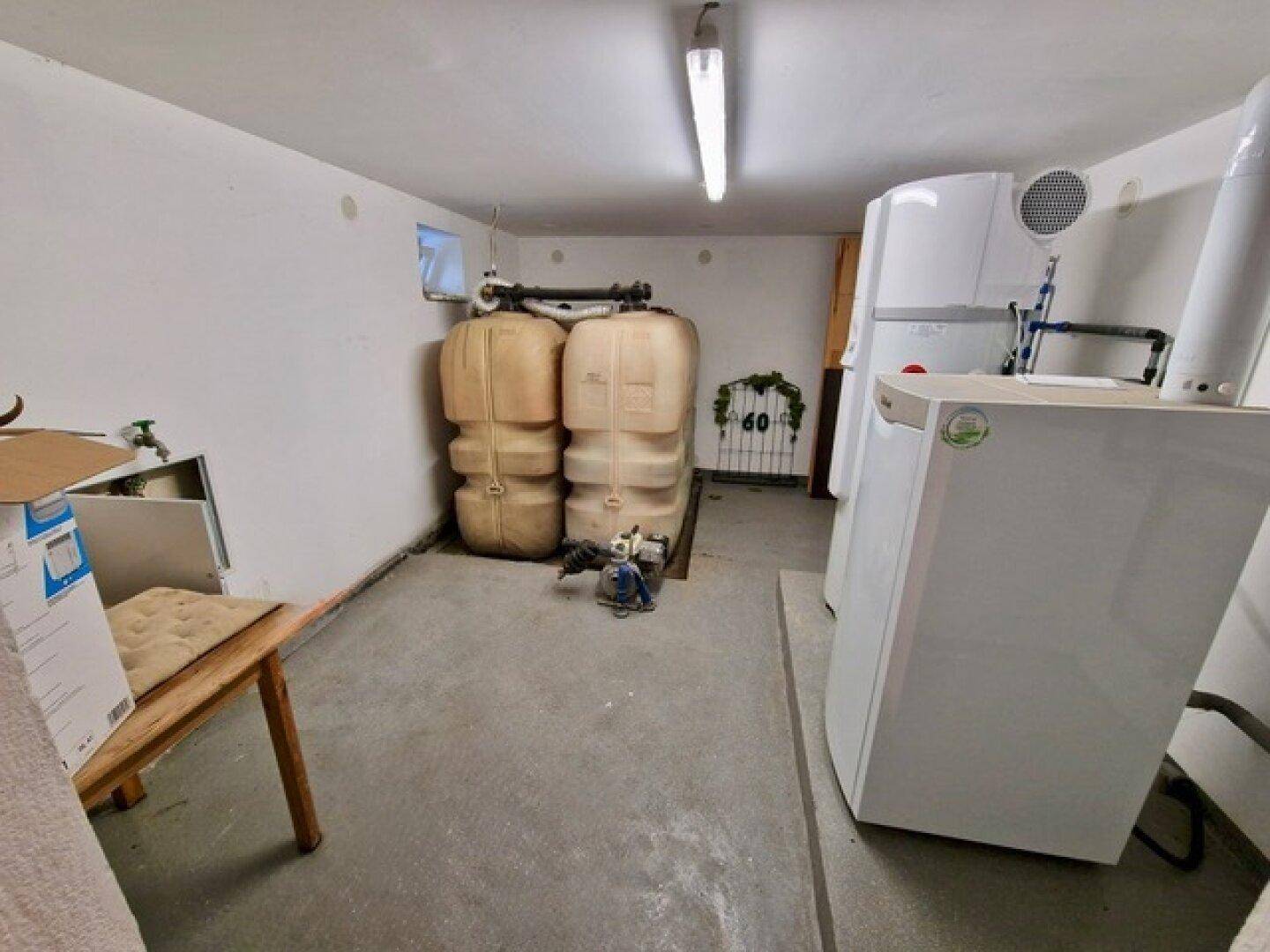 Hauswirtschaftsraum mit Heizungsanlage, Wassertanks und Waschmaschine, funktional und geräumig.