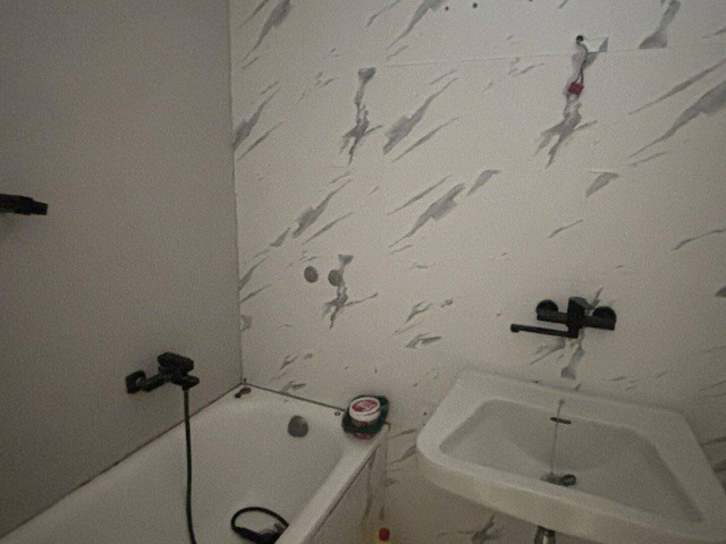 Badezimmer mit Badewanne und Waschbecken, ausgestattet mit modernen Fliesen an den Wänden.