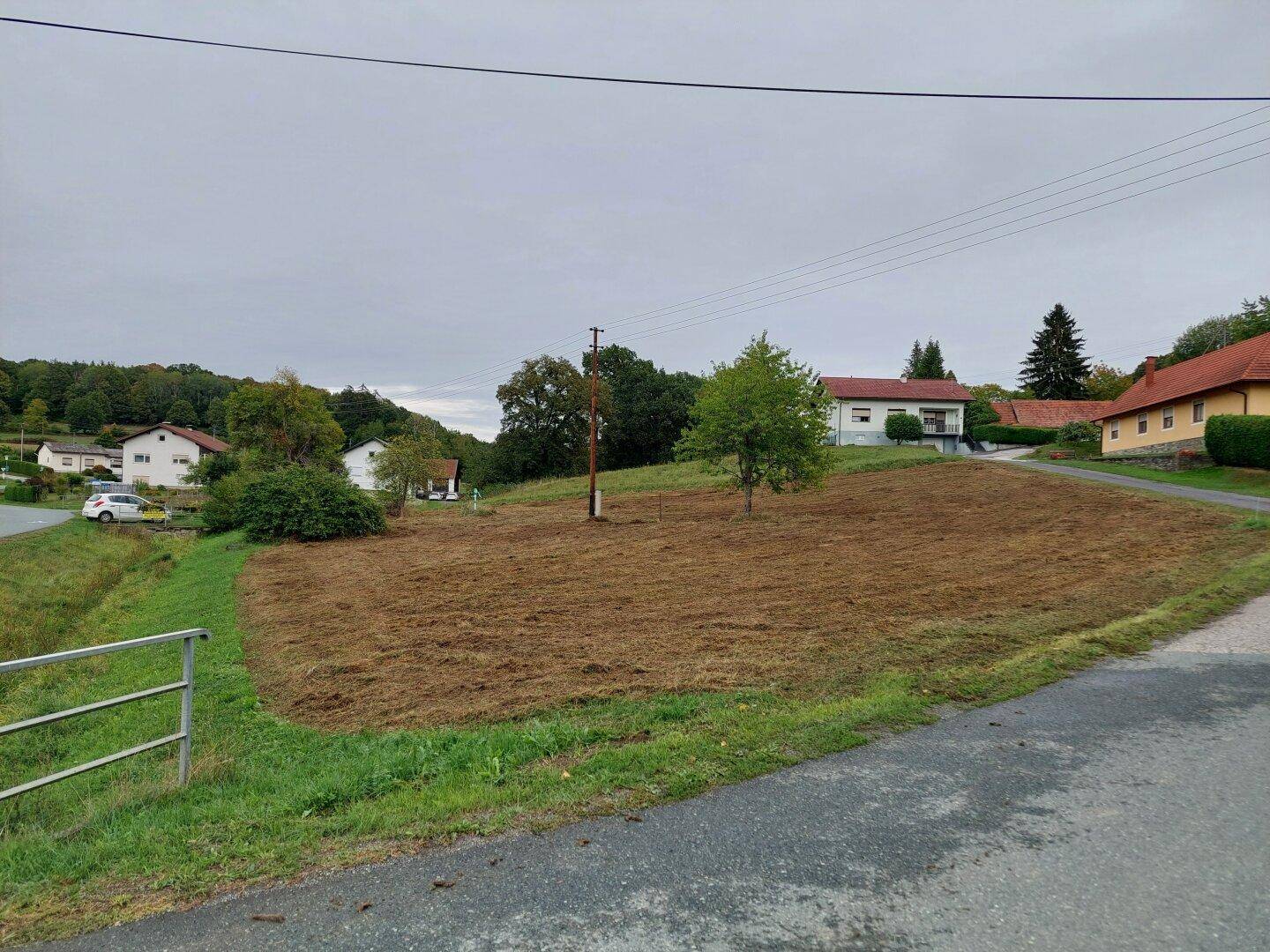 Blick auf ein gepflegtes Grundstück in ländlicher Umgebung mit umliegenden Häusern und Hügeln.