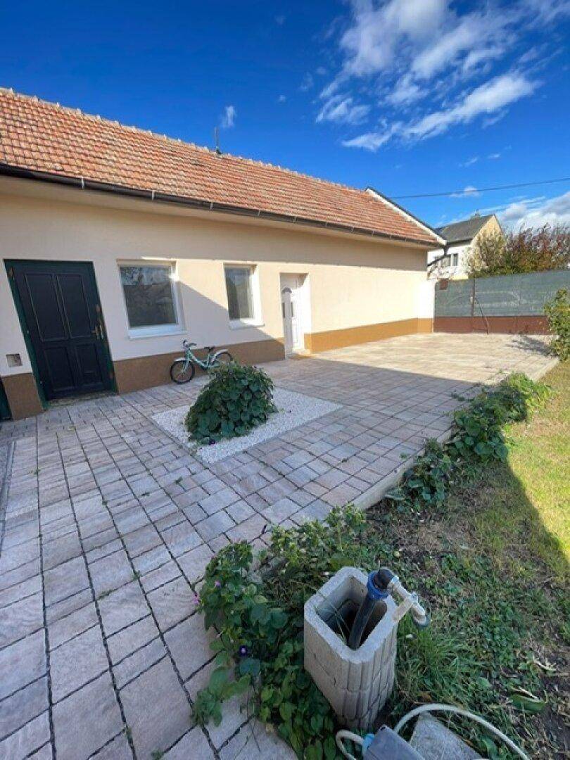 Gepflasterte Terrasse mit einem kleinen Beet und Zugang zum Haus.