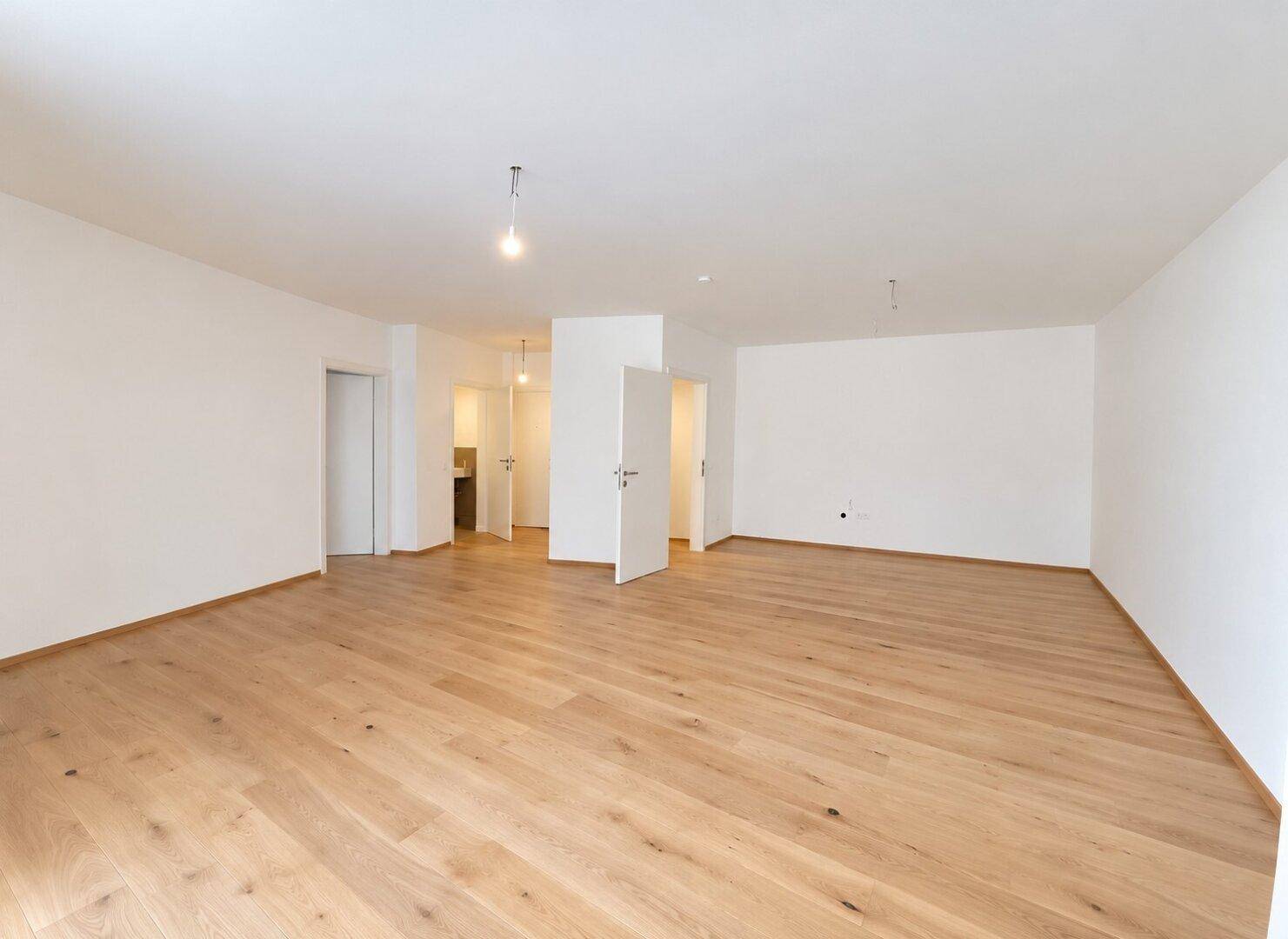 Heller, leerer Raum mit neuem Holzparkettboden und weißen Wänden, bereit zur Einrichtung.