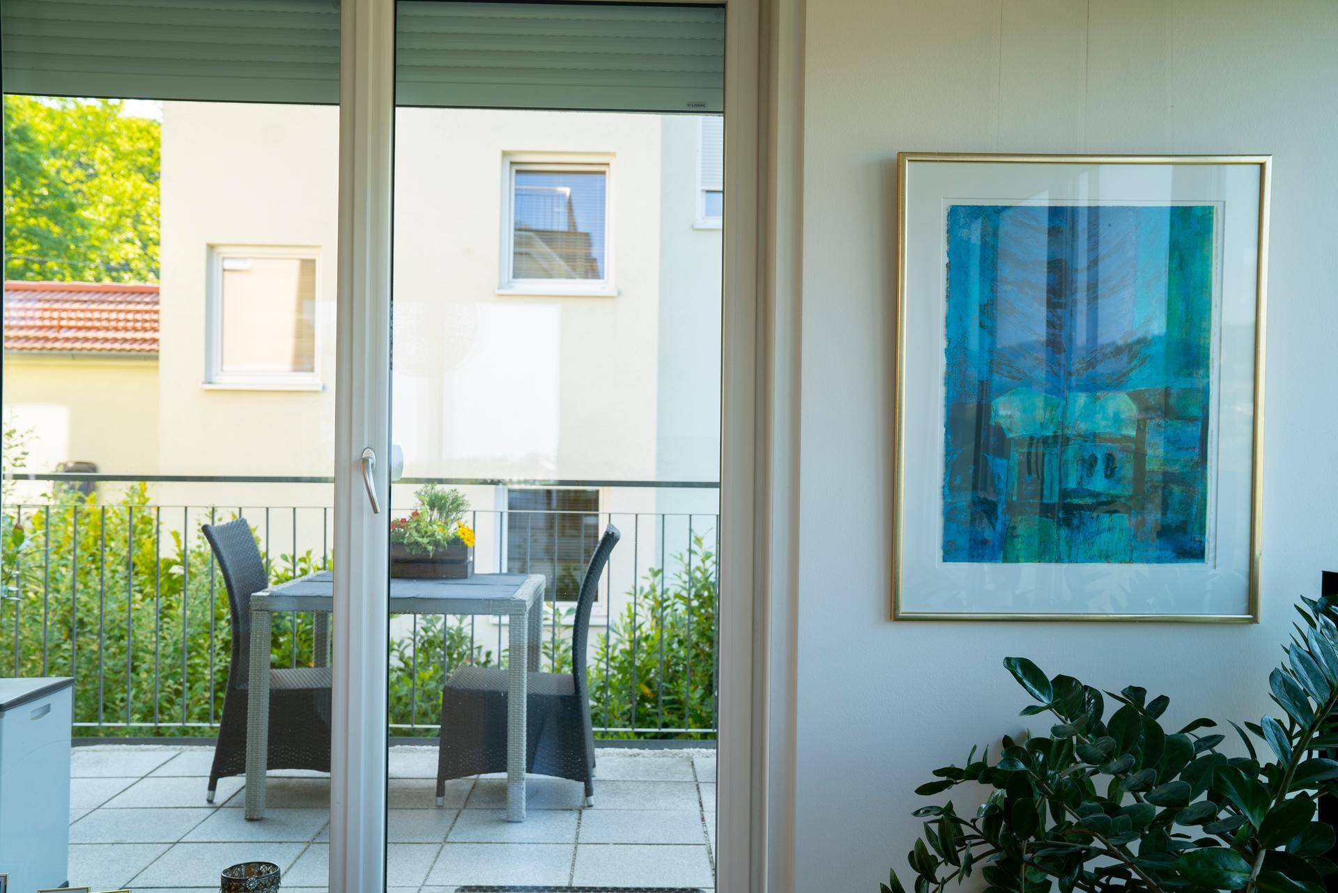 Kleiner Balkon mit Sitzgelegenheiten und Blick auf die umliegenden Gebäude und Grünflächen.