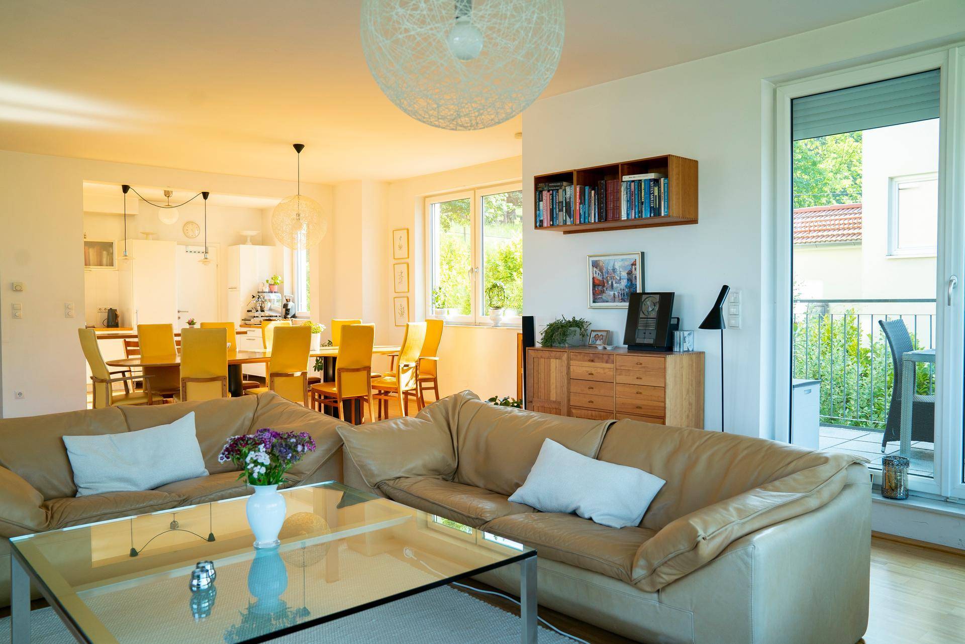 Offener Wohn- und Essbereich mit Ledersofas, Holztisch und Zugang zum Balkon, lichtdurchflutet.