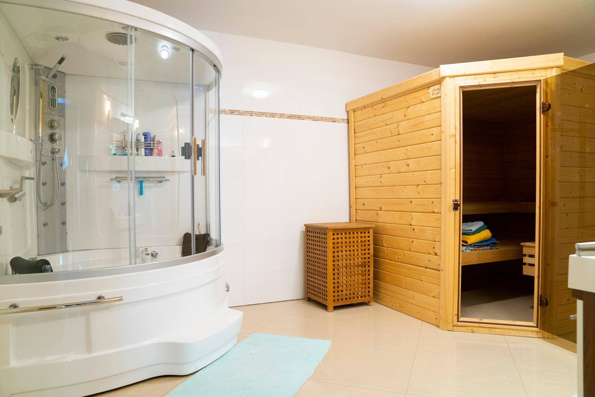 Wellnessbereich mit Duschkabine und holzverkleideter Sauna, ideal zur Entspannung.