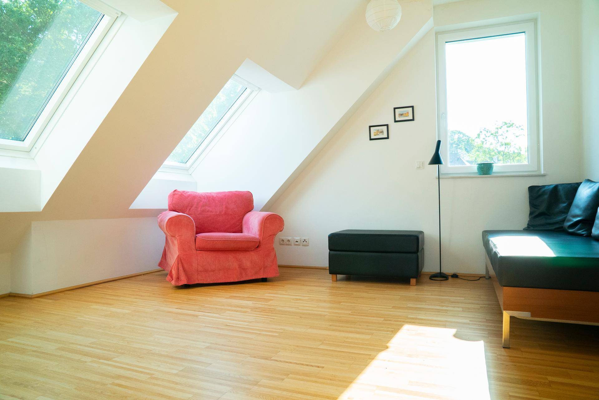 Helles Dachzimmer mit Holzboden, Schrägdach und Dachfenstern, ideal als Schlaf- oder Arbeitsbereich.