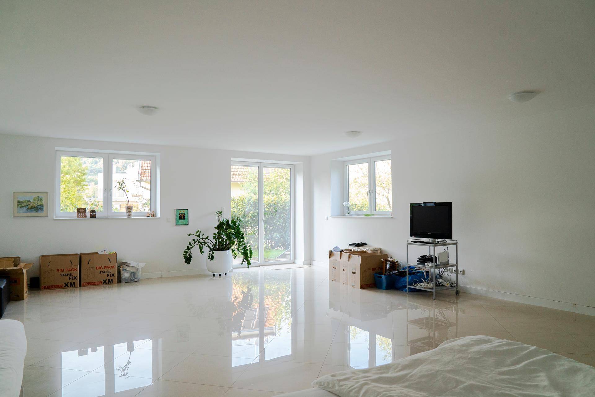 Heller Wohnbereich mit großen Fenstern, Terrassenzugang und glänzenden Fliesenboden.