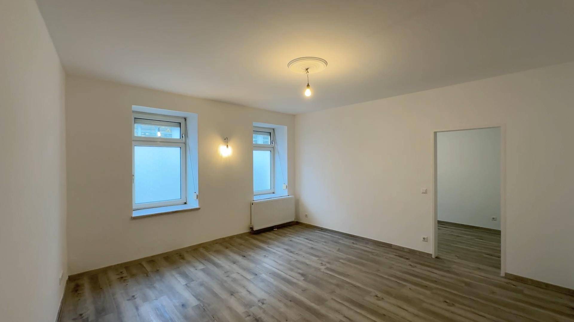 Großes, helles Zimmer mit Laminatboden und zwei Fenstern, bietet vielseitige Nutzungsmöglichkeiten.