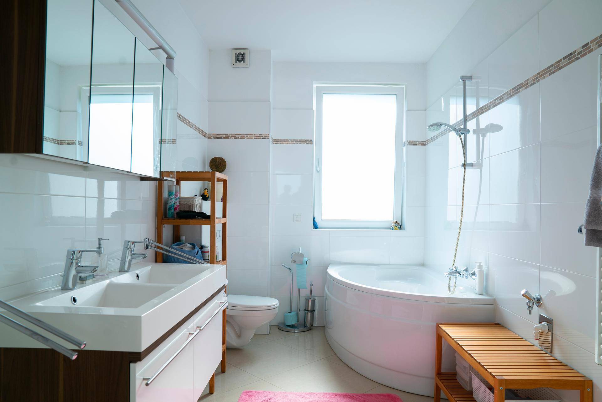 Modernes Badezimmer mit Doppelwaschbecken, Eckbadewanne und Fenster für Tageslicht.