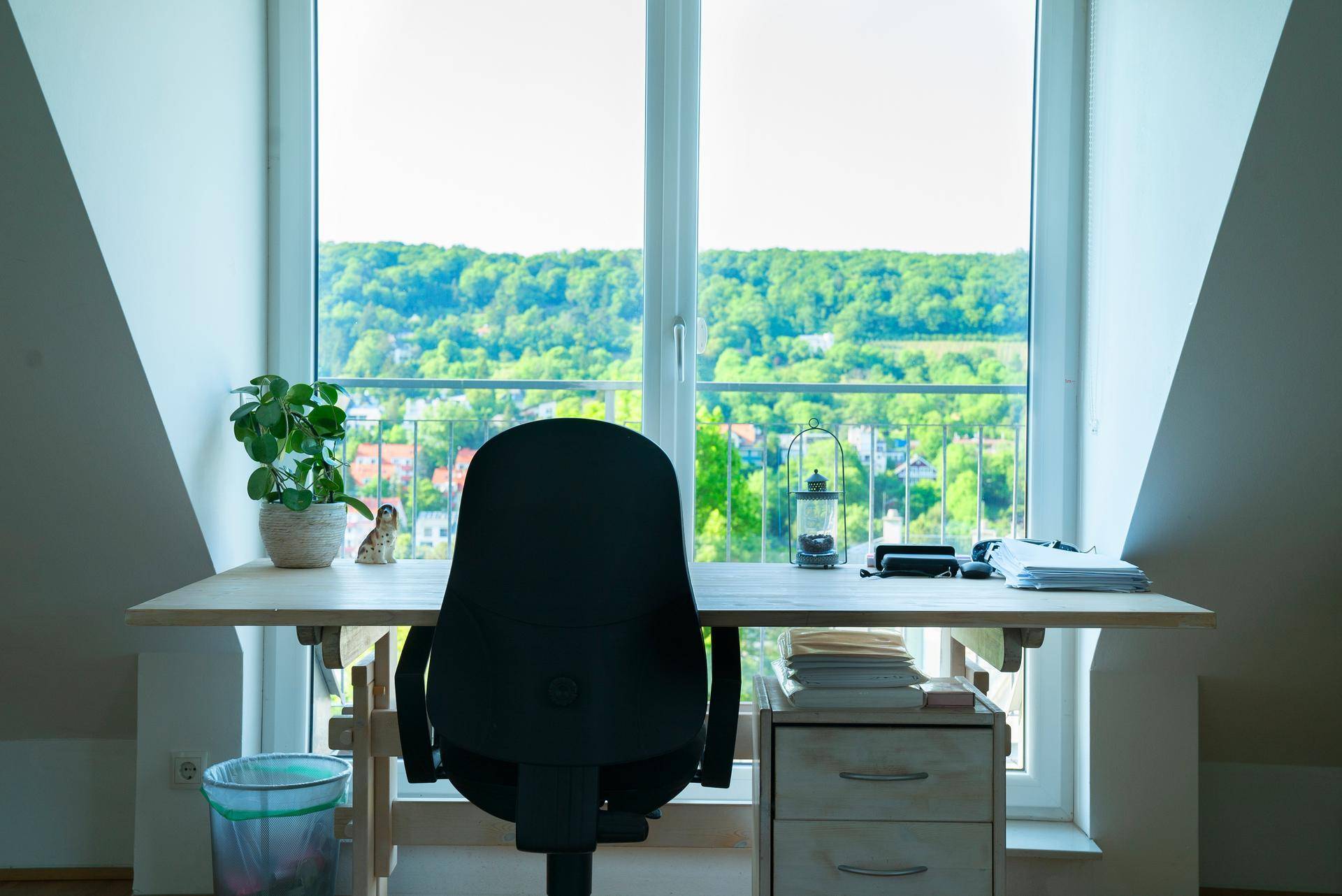 Arbeitsbereich mit Schreibtisch vor einem großen Fenster, das einen weiten Blick ins Grüne bietet.