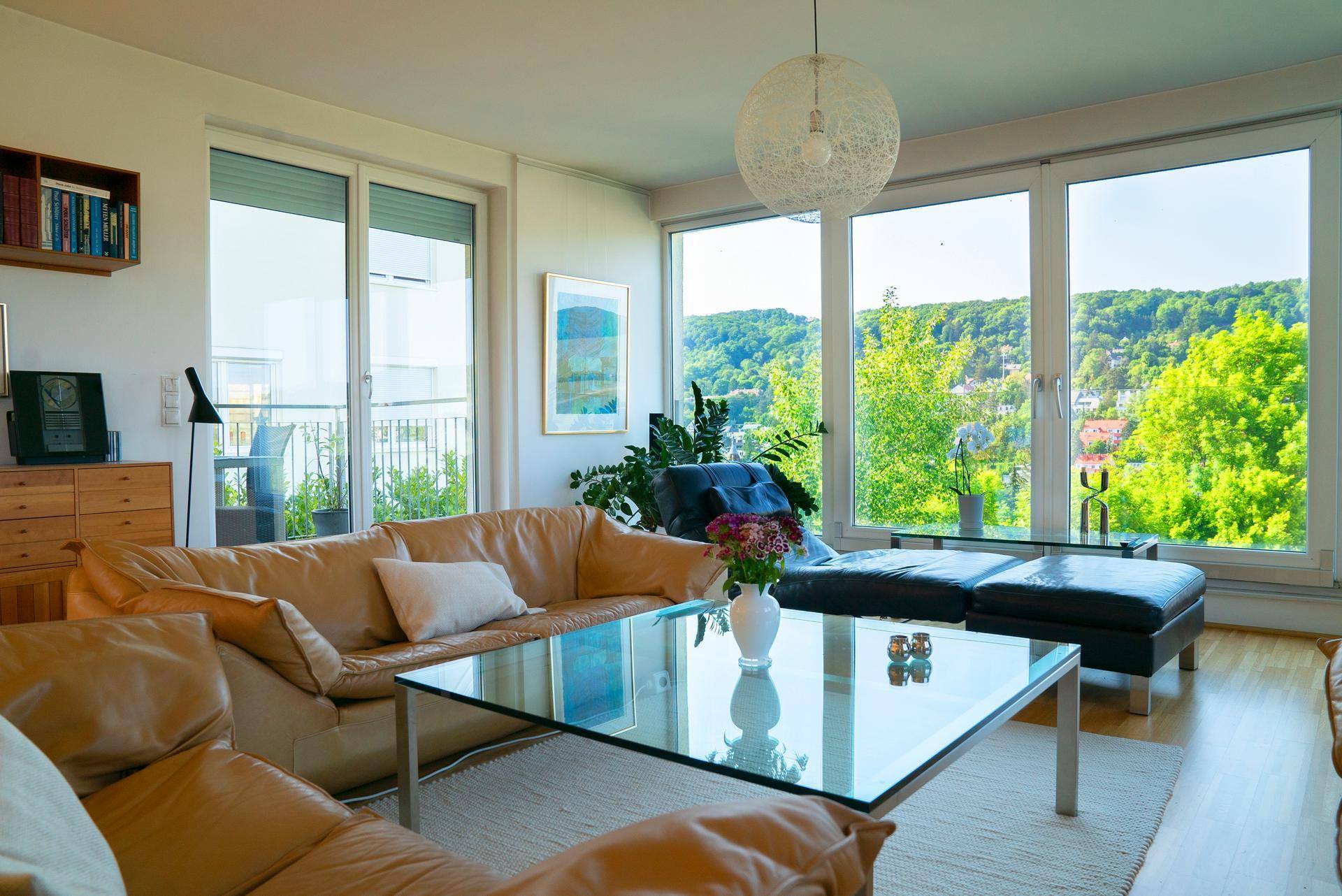 Gemütliches Wohnzimmer mit Ledersofas, Holzboden und Zugang zu einem Balkon mit Weitblick.