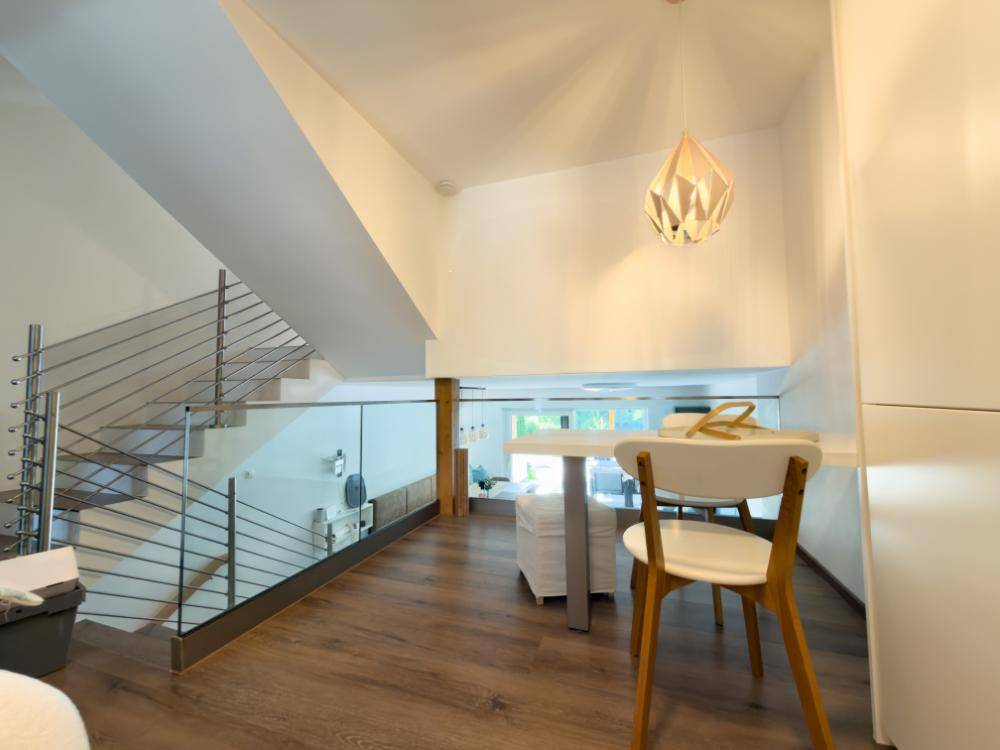 Offener Flurbereich mit moderner Treppe aus Glas und Edelstahl sowie Holzboden.
