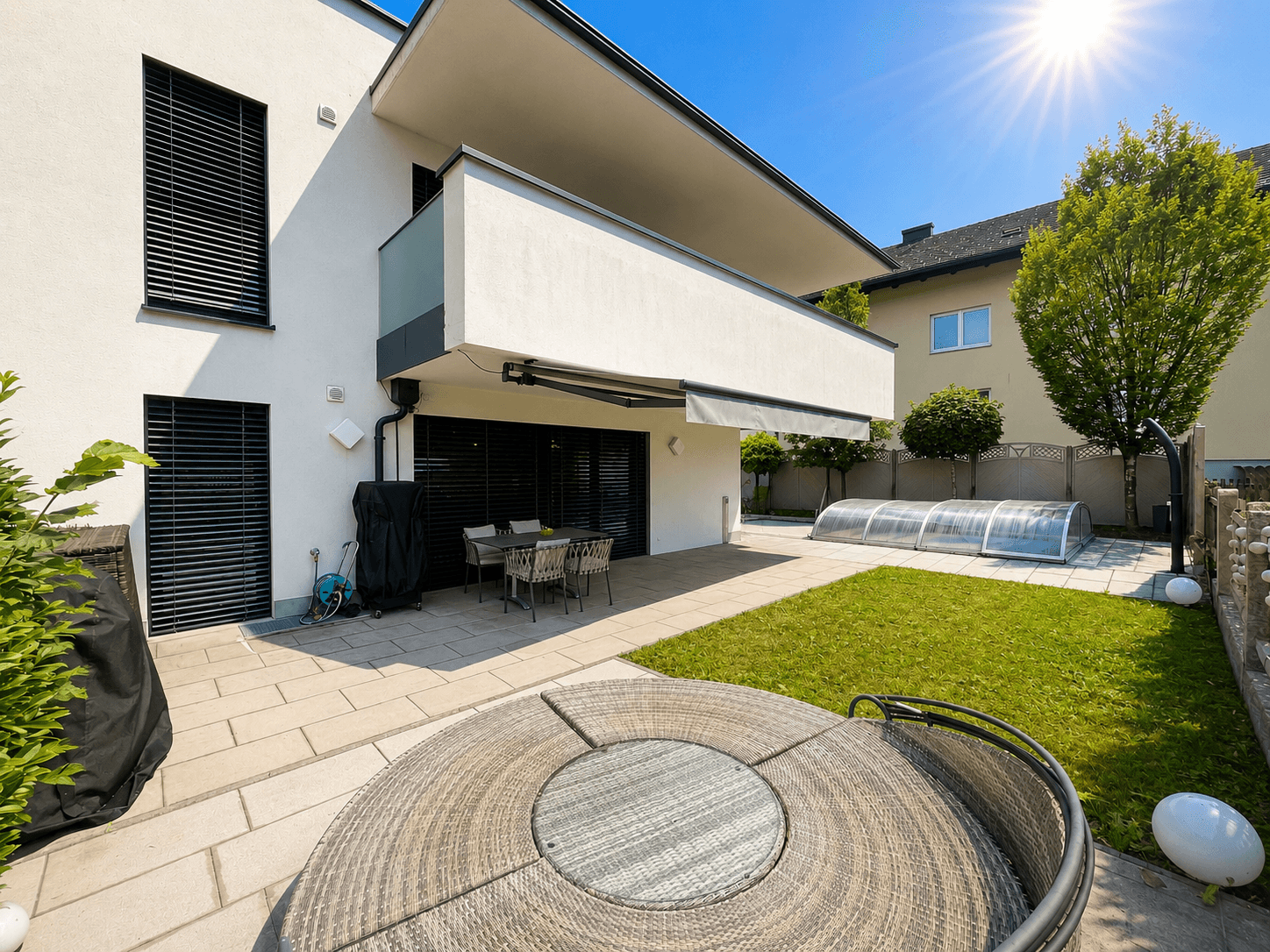 Geräumige Terrasse mit bequemen Outdoor-Möbeln, angrenzendem Rasen und Blick auf den Poolbereich.