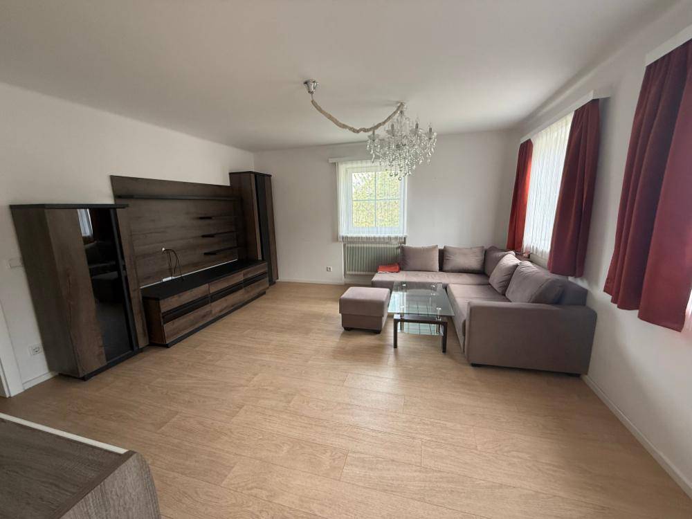 Gemütliches Wohnzimmer mit Sofa, Mediamöbeln und Kronleuchter.