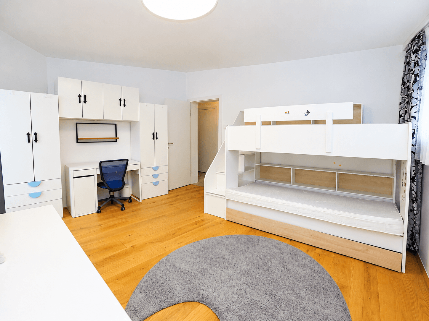 Kinderzimmer mit Etagenbett, Schreibtisch und integrierten Schränken, ideal für Spiel und Lernen.
