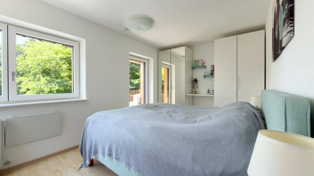 Helles Schlafzimmer mit Doppelbett, Einbauschränken und Zugang zum Balkon.