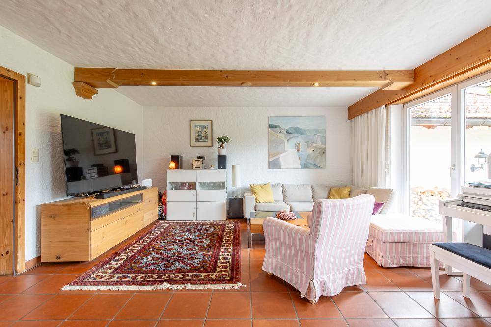 Gemütliches Wohnzimmer mit Terrakottafliesen, sichtbaren Holzbalken und großem Fernseher.