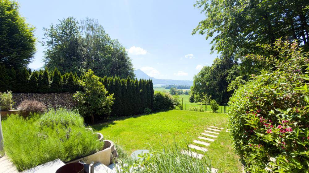 Großer, gepflegter Garten mit Rasenfläche, Hecken und weitem Blick auf die Landschaft.