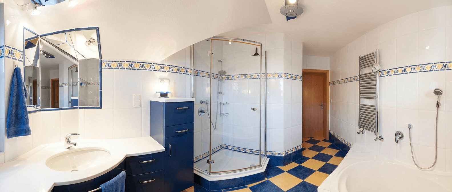 Geräumiges Badezimmer mit blauen und weißen Fliesen, Duschkabine und Badewanne.