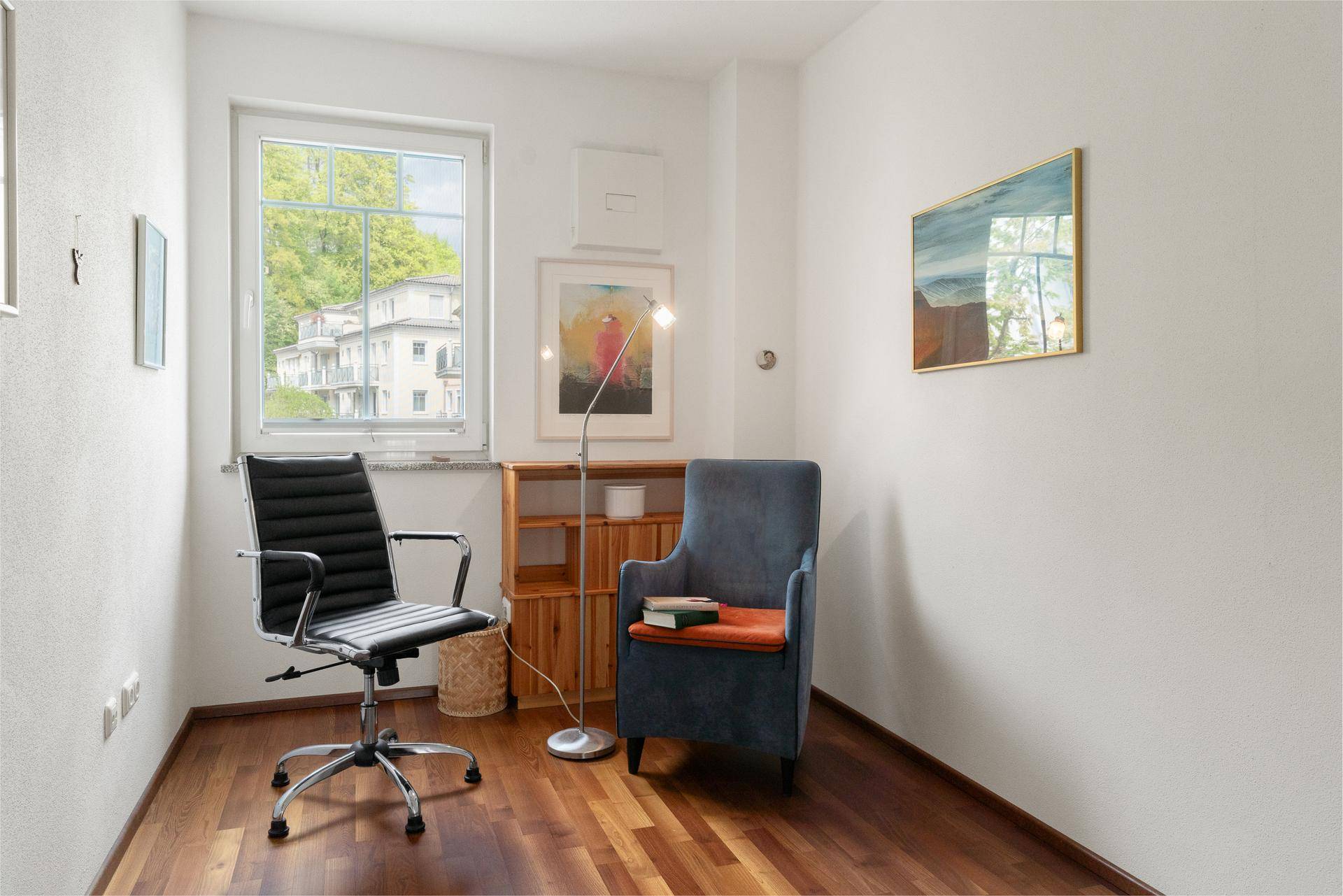 Gemütliches Büro mit Schreibtischstuhl, Sessel und Blick ins Grüne.