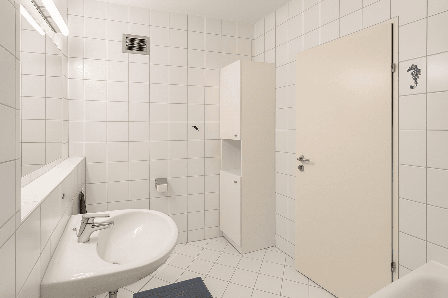 Helles Badezimmer mit weißen Fliesen, Waschbecken und Spiegelschrank.