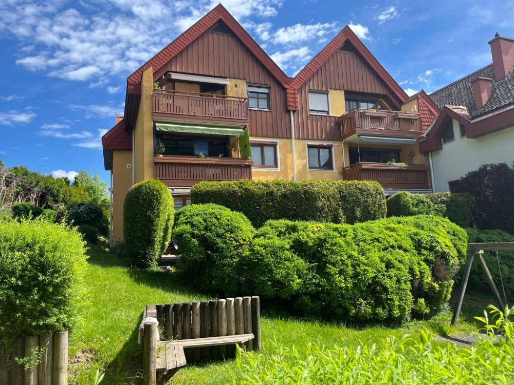 Mehrfamilienhaus mit mehreren Balkonen und gepflegter Grünanlage.