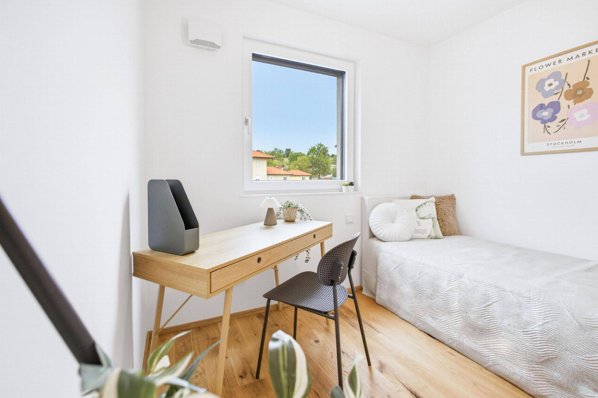 Freundliches Zimmer mit Schreibtisch, Einzelbett und Blick auf die Umgebung.