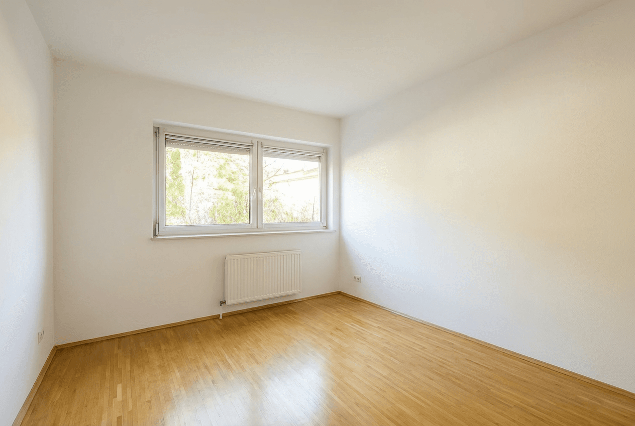 Helles Zimmer mit Parkettboden und großem Fenster, ideal als Schlaf- oder Arbeitszimmer.