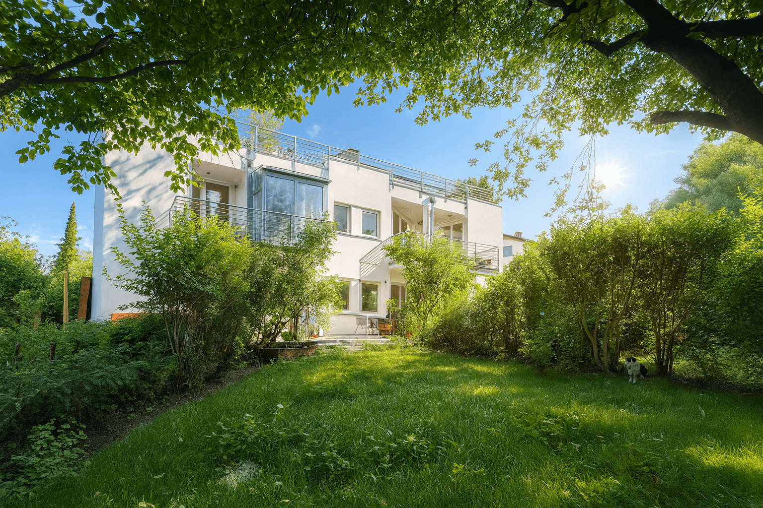 Gepflegter Gartenbereich mit Rasenfläche und Sträuchern vor einer modernen Wohnanlage.