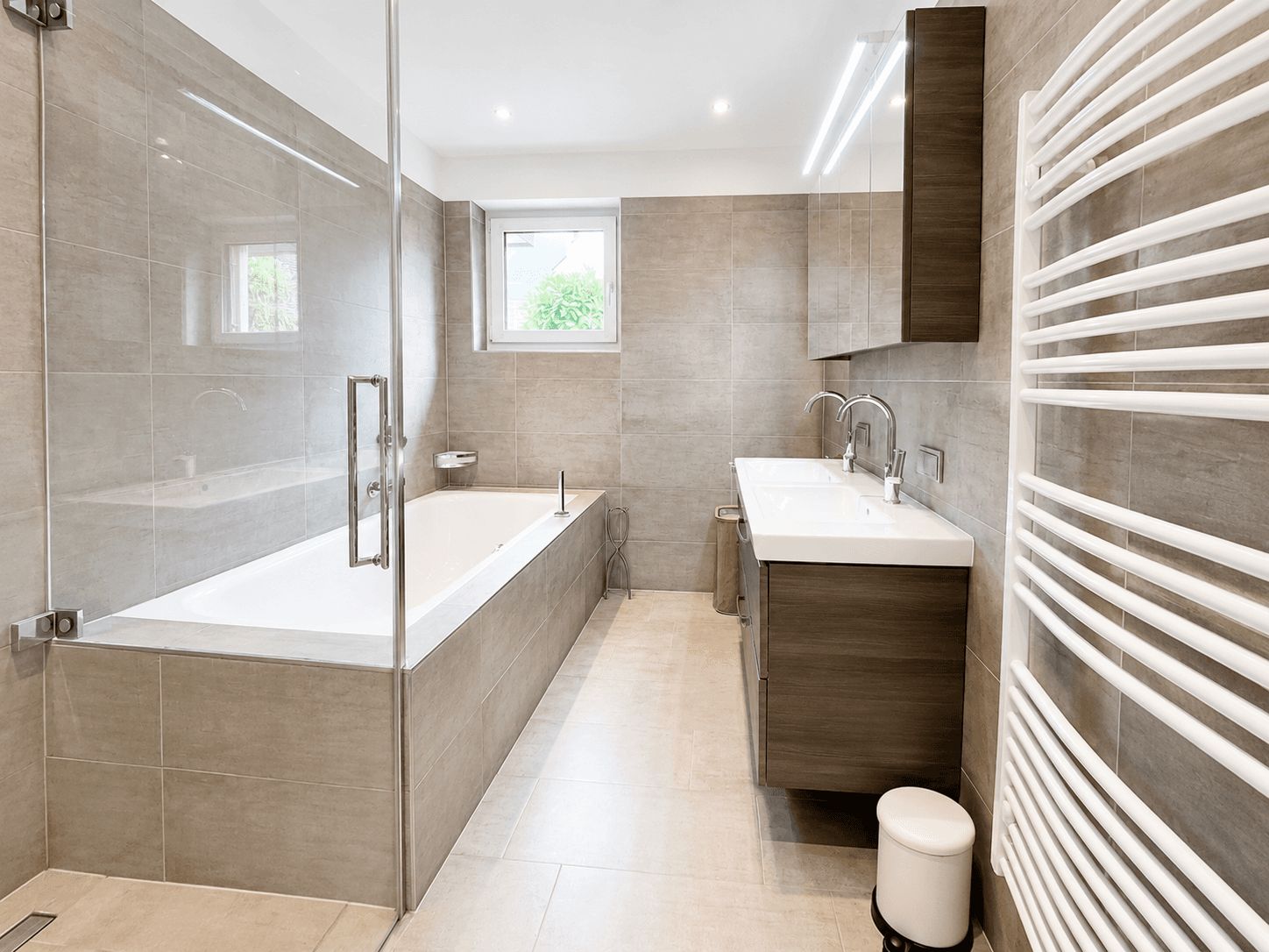 Modernes Badezimmer mit Badewanne, begehbarer Dusche, Doppelwaschbecken und Handtuchheizkörper.