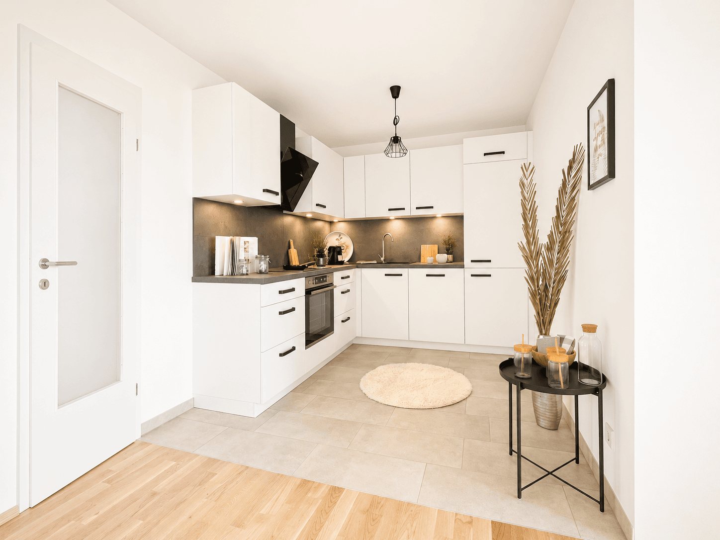 Moderne weiße Küche mit grauer Arbeitsplatte, integrierten Geräten und Fliesenboden.