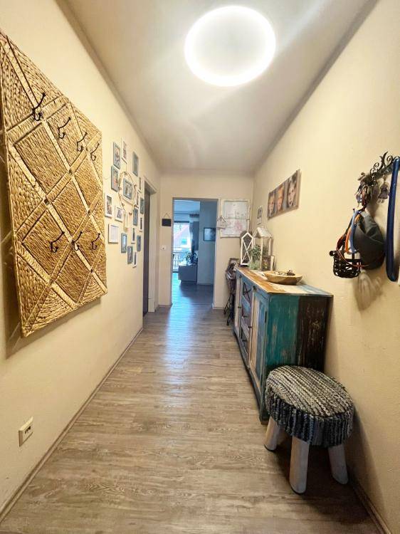 Langer Flur mit Holzboden, Garderobe und dekorativen Elementen.