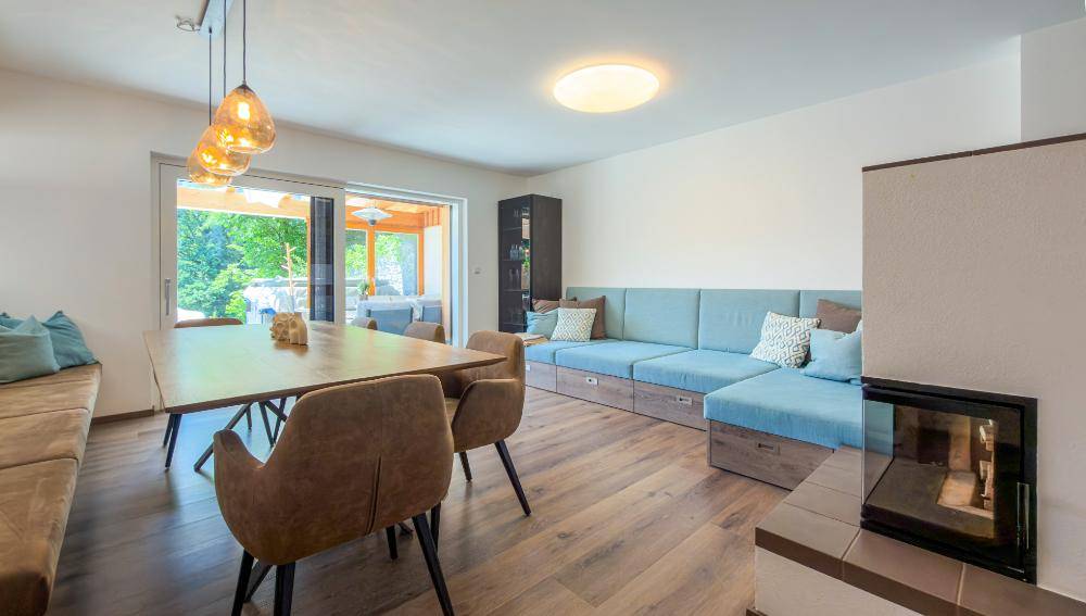 Gemütlicher Wohnbereich mit Ecksofa, Esstisch und Zugang zur überdachten Terrasse.