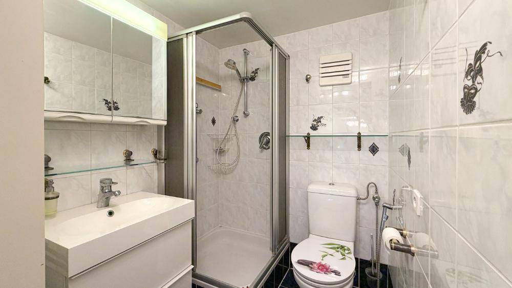 Kleines Badezimmer mit Dusche, WC und Waschbecken.