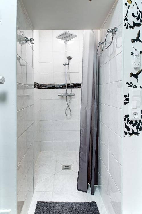 Duschbereich mit Regendusche und weißen Fliesen in einem modernen Badezimmer.
