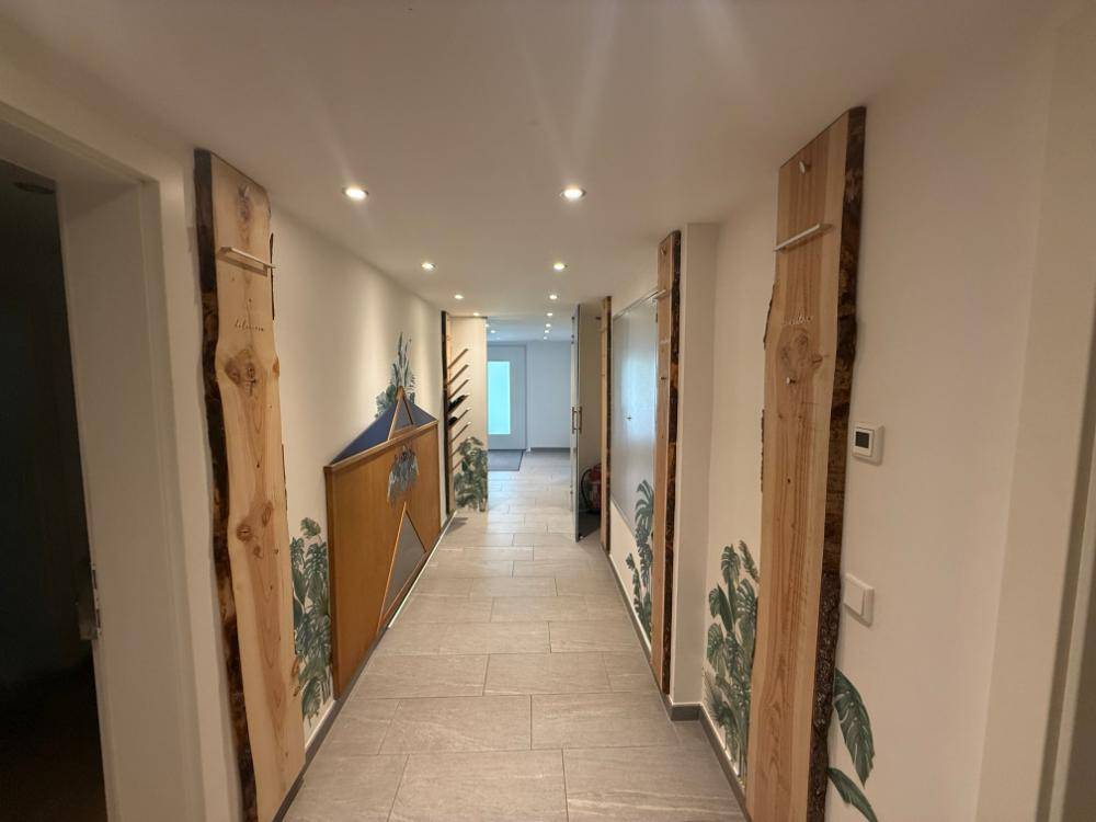 Heller Flur mit modernen Fliesen, Holzverkleidungen und indirekter Beleuchtung.
