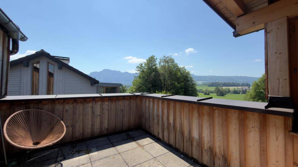 Balkon mit Holzboden und Geländer, bietet einen weiten Blick auf die Berge und Landschaft.