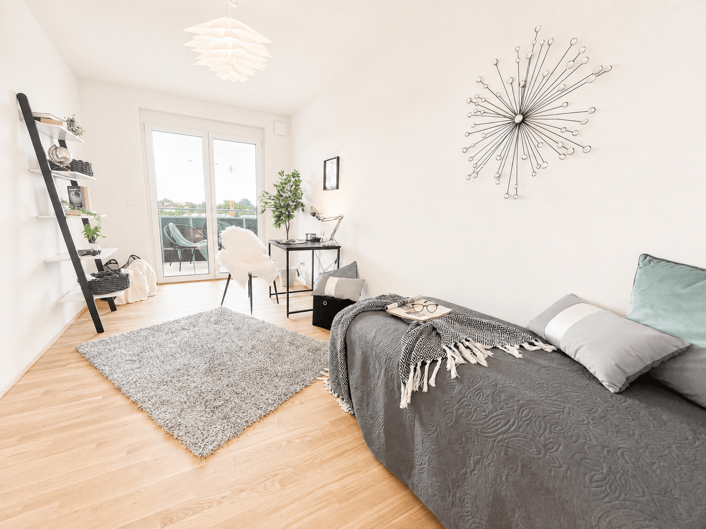 Helles Zimmer mit Holzboden, Zugang zum Balkon und modernem Schreibtischbereich.
